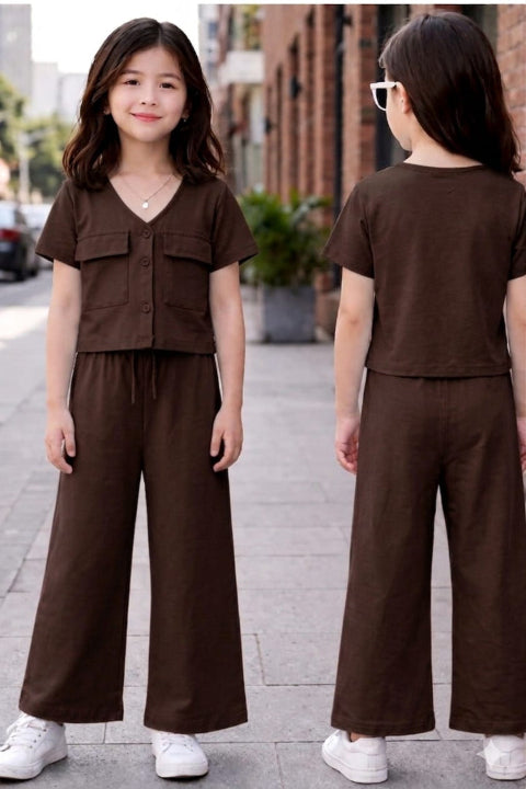 Girl wearing a brown outfit standing on a street with a brick building in the background.